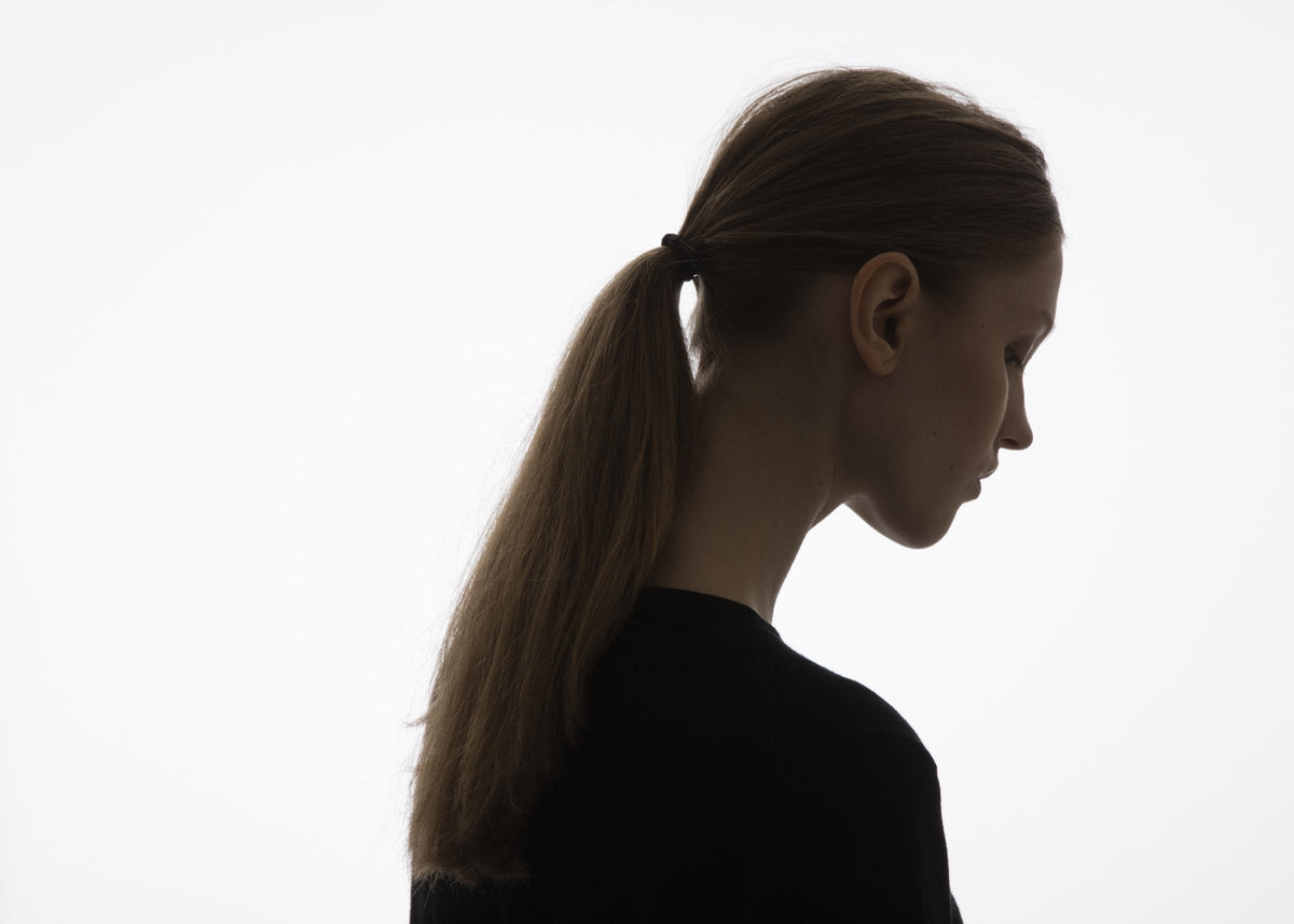 Profil einer Frau im Gegenlicht vor hellem Hintergrund