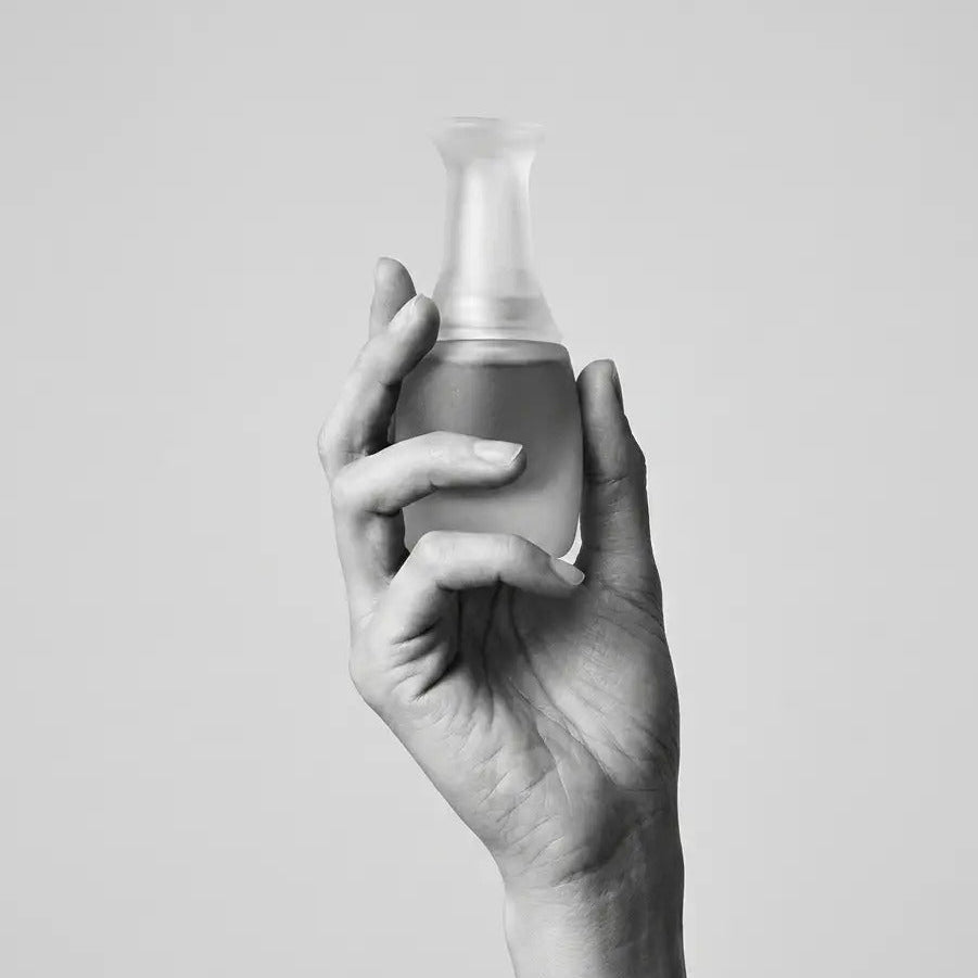 Less Face Oil Flakon in einer Hand